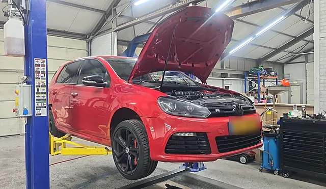 Rode Volkswagen Golf met open motorkap